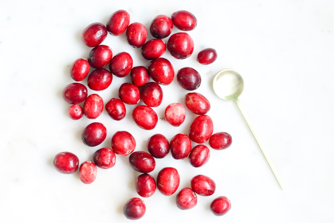 Red berries in a bowl beside a cup, reflecting uva ursi for urinary tract health traditions