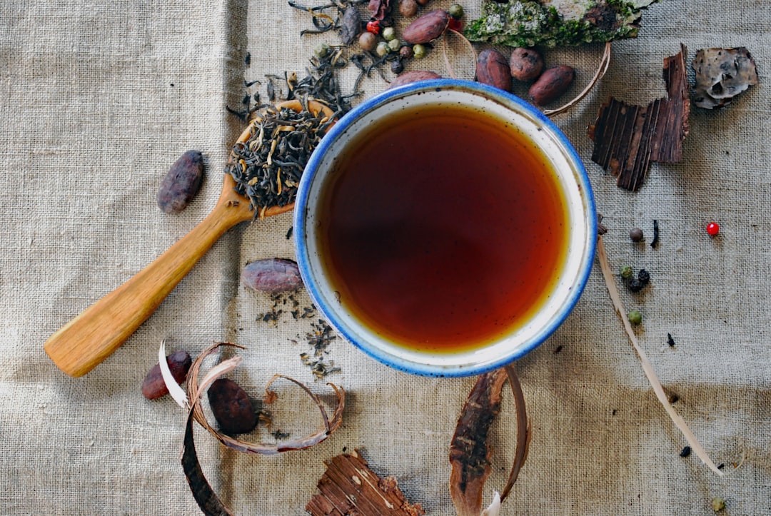 A cup of herbal infusion surrounded by dried herbs and spices