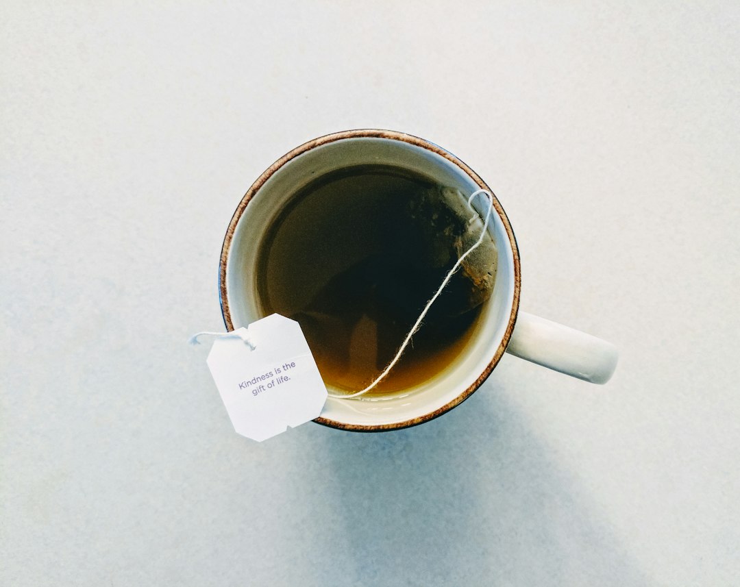 A covered mug of hot herbal infusion steeping on a wooden table