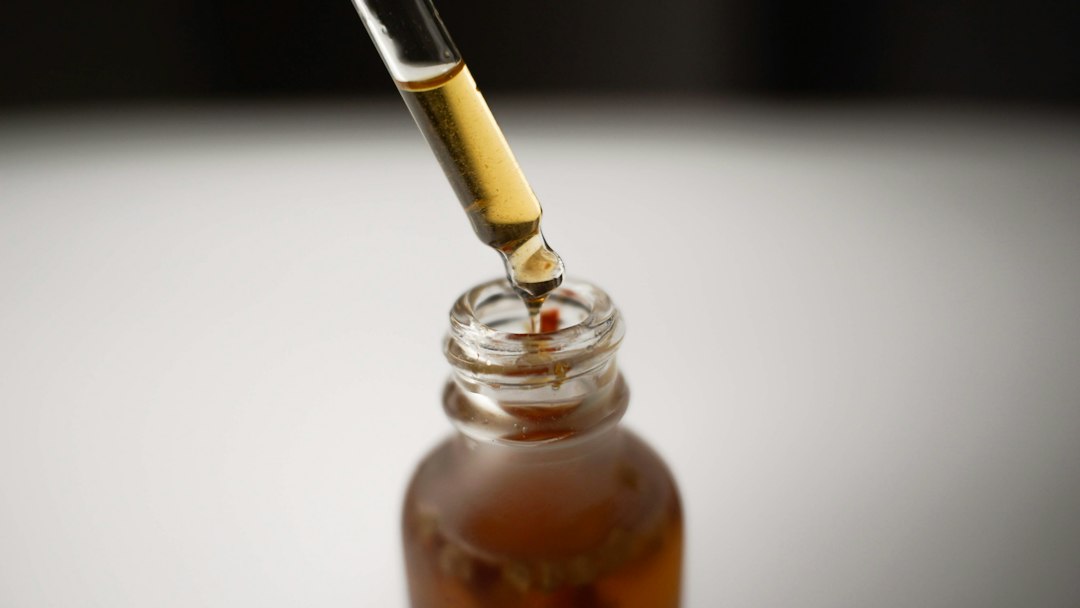 Dropper releasing herbal tincture into an amber bottle